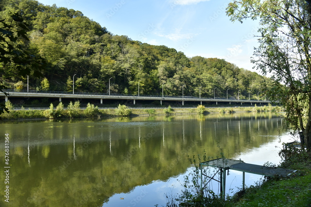Reflet dans les eaux de la Meuse de la colline boisée et de l'autoroute à Lustin Reflet dans les eaux de la Meuse de la colline boisée et de l'autoroute à Lustin