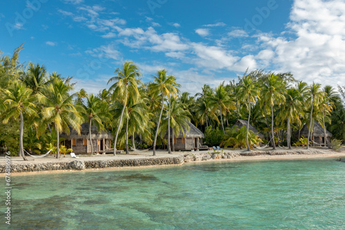French Polynesia Tikehau atoll with sandy beach  beach bungalows  palm trees and blue sky.