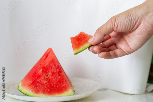 The water melom cut into slices with a womam hand