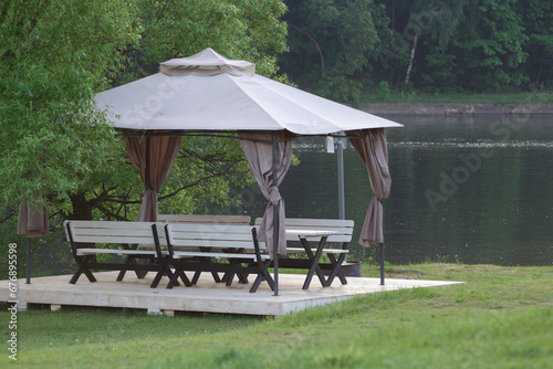 Gazebo with table and benches on the river bank..Picturesque place for camping in nature.