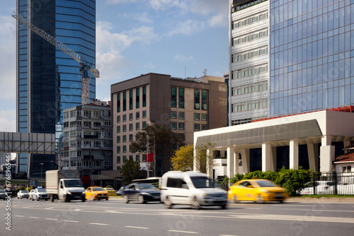 Cars quickly rush along the road against the backdrop of skyscrapers in a prestigious area of the city.