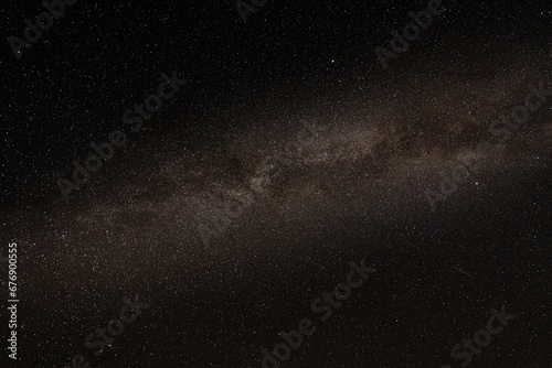 some white stars and milky on a dark sky above a plain with trees