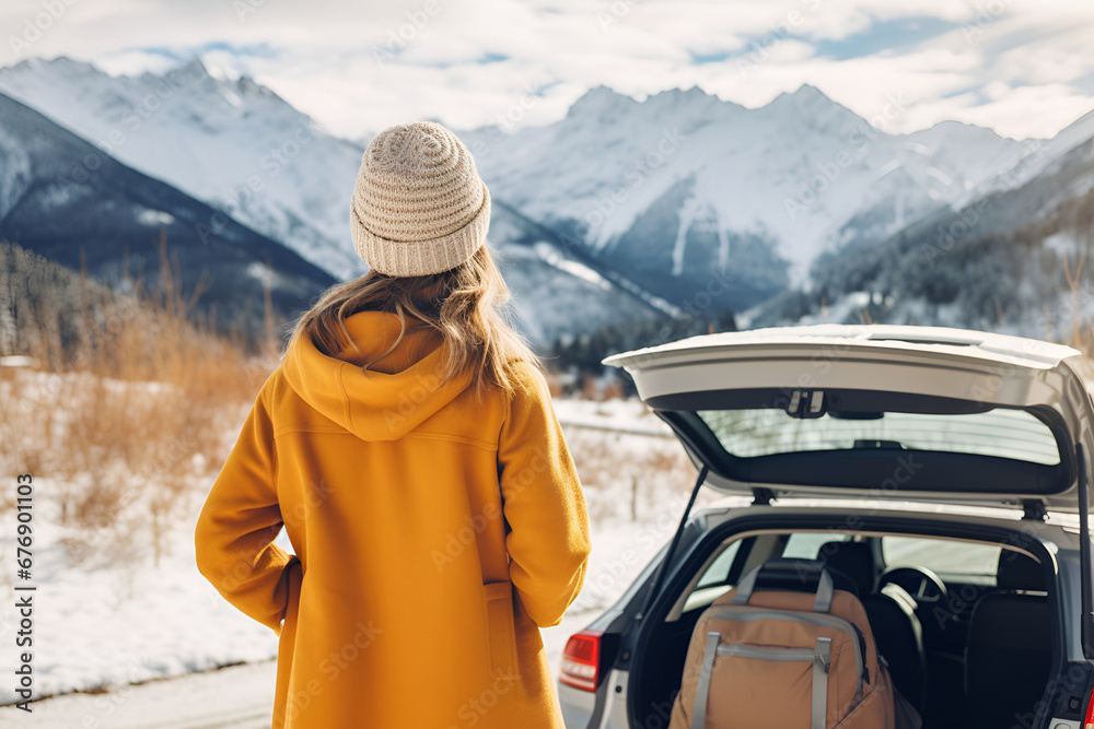 A woman traveling by car looks at the winter snowy mountains