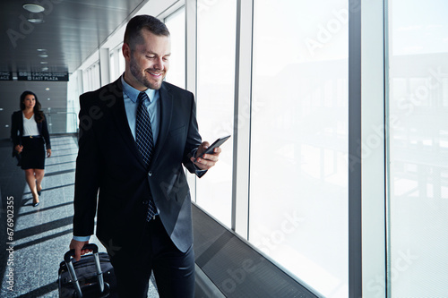 Business man, phone and travel in airport window for reading, thinking and contact in corridor with smile. Entrepreneur, luggage and smartphone for flight schedule and global immigration in London