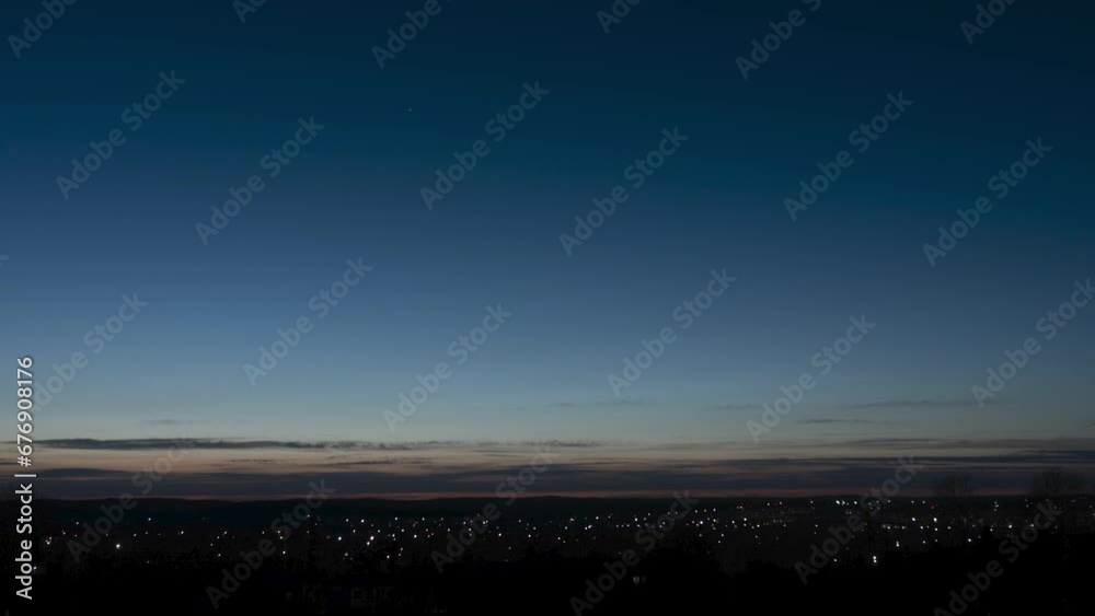 Dramatic hyperlapse of the golden hour of sunset. The image shows the lights of the night life of a small town and the lights of cars in the neighborhood.