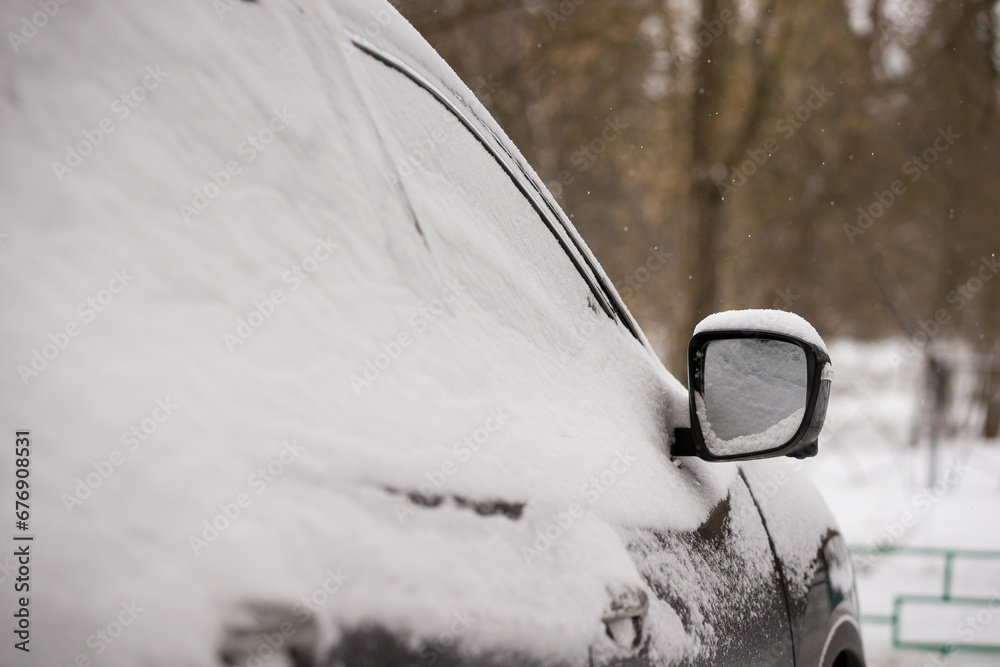 Snowfall covered cars and roads. Door mirror and car glass in the snow. The beginning of winter. Road safety