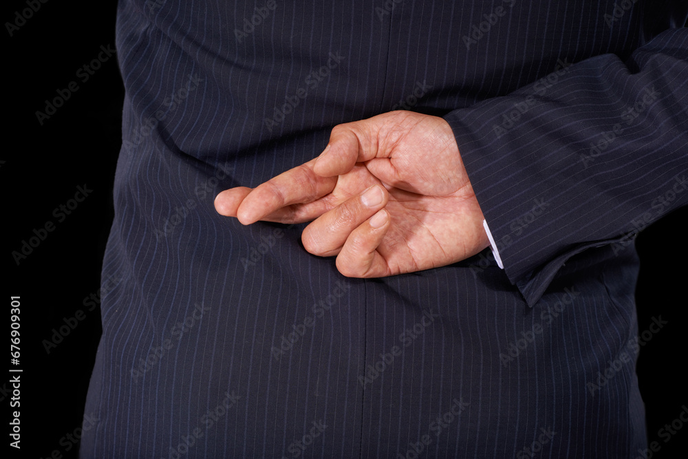 Fototapeta premium Closeup, business and man with fingers crossed, fraud and lawyer with oath, corrupt and dishonesty. Person, corporate professional or model in a suit, hand gesture or liar on a dark studio background
