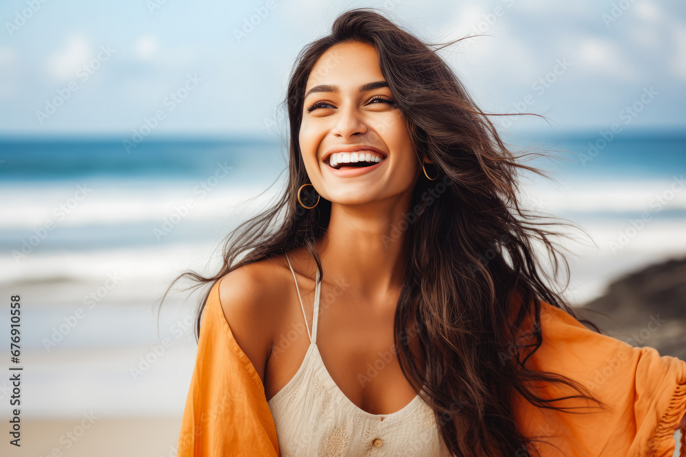 Happy beautiful young indian woman smiling at the beach. Summer at the beach, positivity and happy carefree lifestyle.