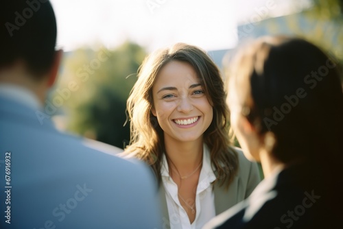 Attractive young female executive wearing a suit talking with coworkers 