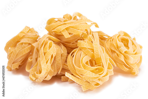 A Pile of Classic Italian Raw Egg Fettuccine - Isolated on White Background. Dry Twisted Uncooked Pasta. Italian Culture and Cuisine. Raw Golden Macaroni Pattern - Isolation