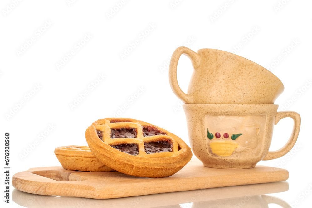 Two shortbread cookies with jam on a wooden kitchen board with two ceramic cups Two shortbread cookies with jam on a wooden kitchen board with two ceramic cups