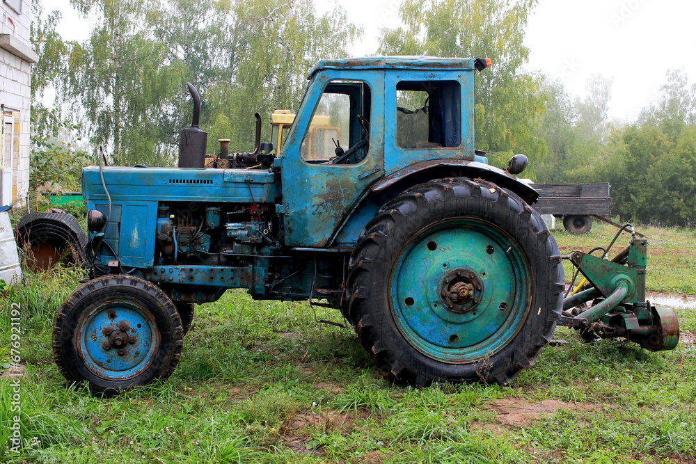 Photo of a blue old tractor on trees. Photo of a blue old tractor on trees.