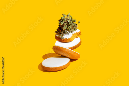 Delicious gingerbread cookies stuffed with cannabis. Creative concept on yellow background