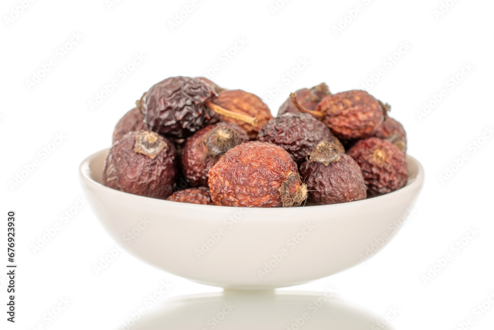 Several dry rosehip berries in a white ceramic saucer, macro, isolated on white background. Several dry rosehip berries in a white ceramic saucer, macro, isolated on white background.
