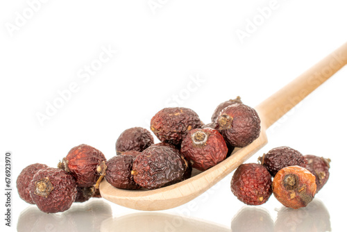 Several dry rosehip berries with wooden spoon, macro, isolated on white background.