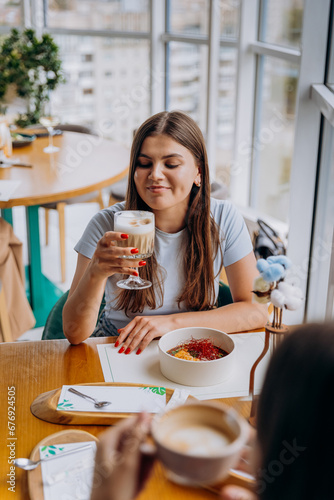 Young beautiful stylish woman drinking coffee while sitting in restaurant during meeting with friend