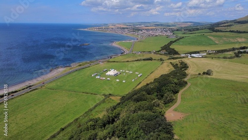 Fototapeta Naklejka Na Ścianę i Meble -  Aerial drone view of green fields with a blue seascape in Scotland in sunlight