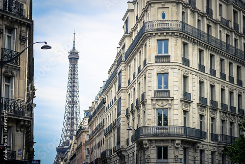 View with a Haussmann-style building (flat) with the Eiffel Tower (Tour Eiffel) in the background in Paris, France on July, 16, 2023.