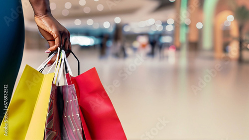 Close na mão de uma mulher carregando sacolas de compras em um ambiente de shopping.