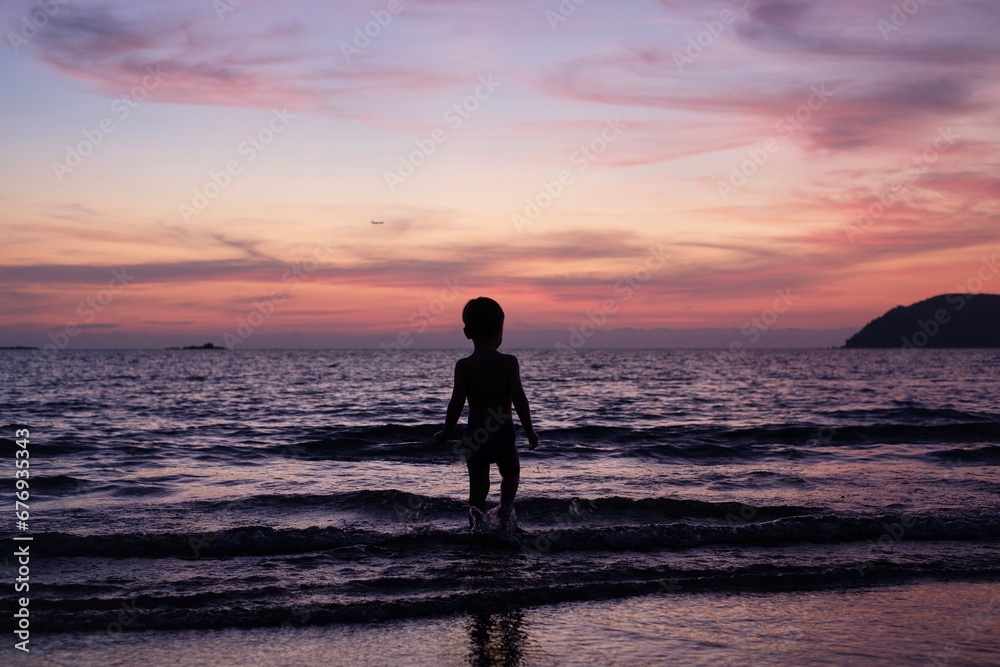 Child playing by the sea at sunset
