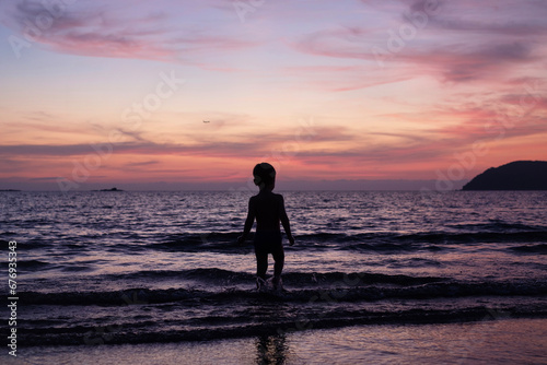 Child playing by the sea at sunset