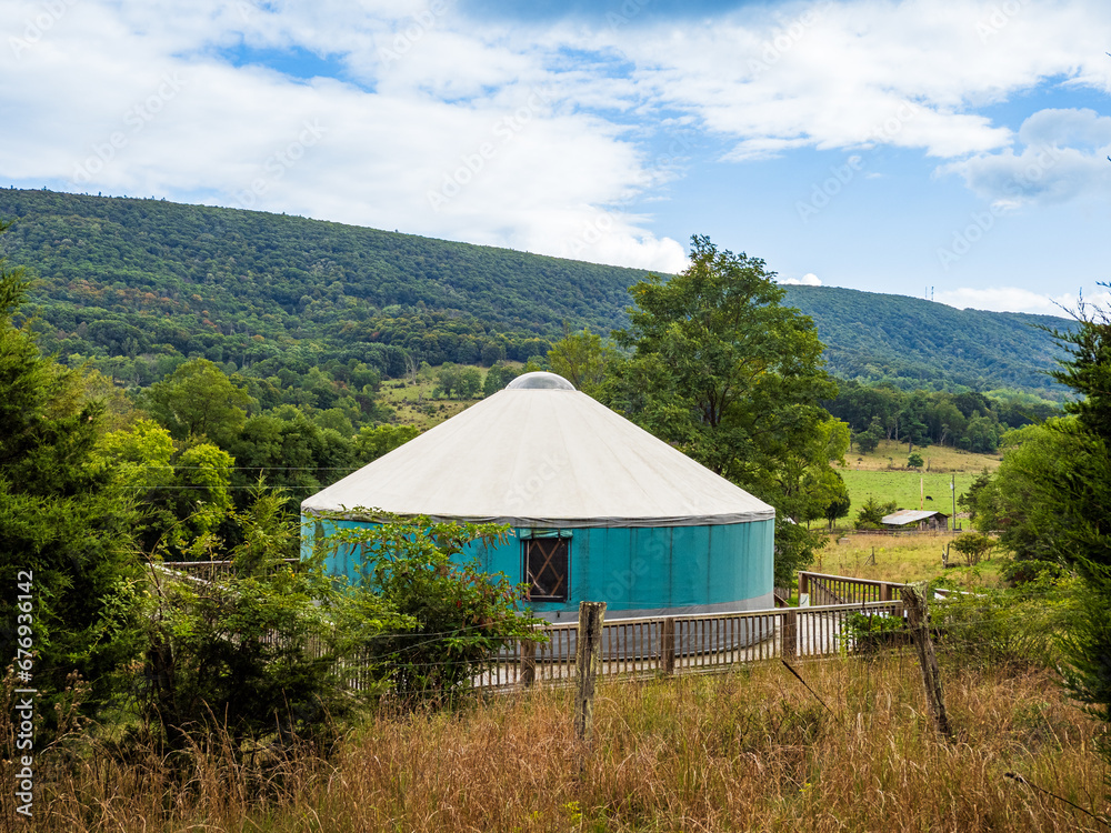 A yurt, an old type of tent-like house, in Mathias, West Virginia, with the hills and forest as backdrop.