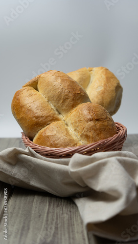 Traditional Chilean Marraqueta bread, in a bread basket with white background on gray wooden table.