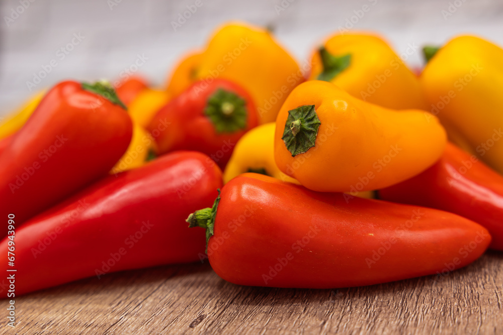 delicious and healthy red, orange and yellow sweet peppers on a wooden cooking board ready to be prepared in one recipe
