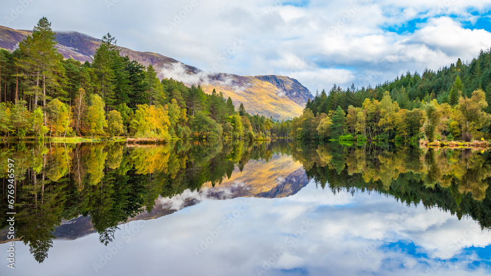 Perfect reflection on the lake Glencoe Lochan in Scotland, with autumn trees and mountain in the background