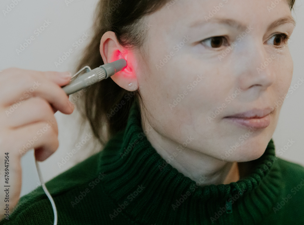 A young girl treats her ear with an infrared light device.