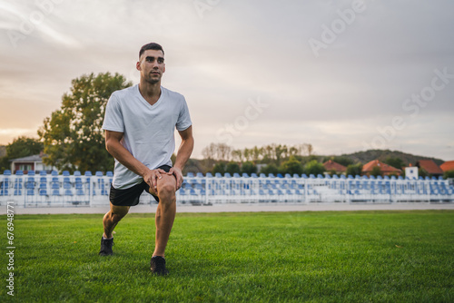 one man male athlete stretch outdoor at stadium track