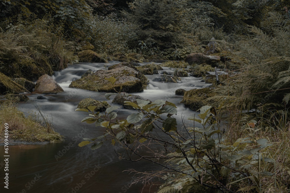 Long exposure shot of the flowing water of a rocky river in the forest Long exposure shot of the flowing water of a rocky river in the forest