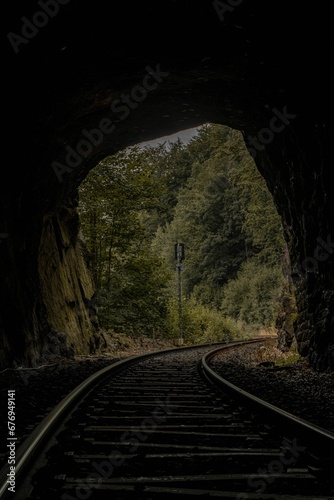Vertical dramatic shot of the railway trails through a tunnel in the green rainforest