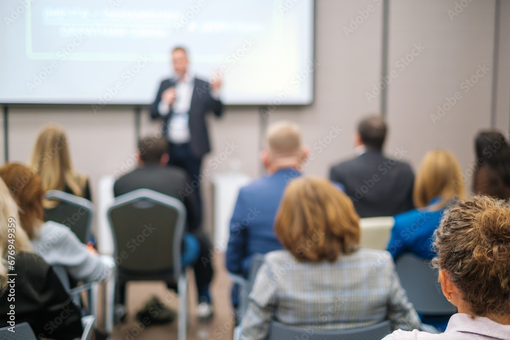 Back view of businesswoman attending presentation with diverse participants in conference hall Back view of businesswoman attending presentation with diverse participants in conference hall