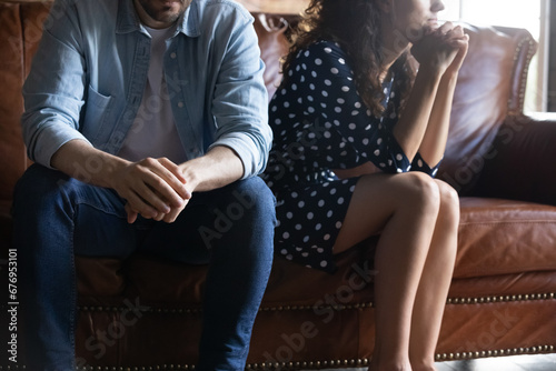 Cropped close up of frustrated millennial couple sitting on couch after quarrel, ignoring each other, upset unhappy man and woman not talking, family conflict, break up, bad relationship concept