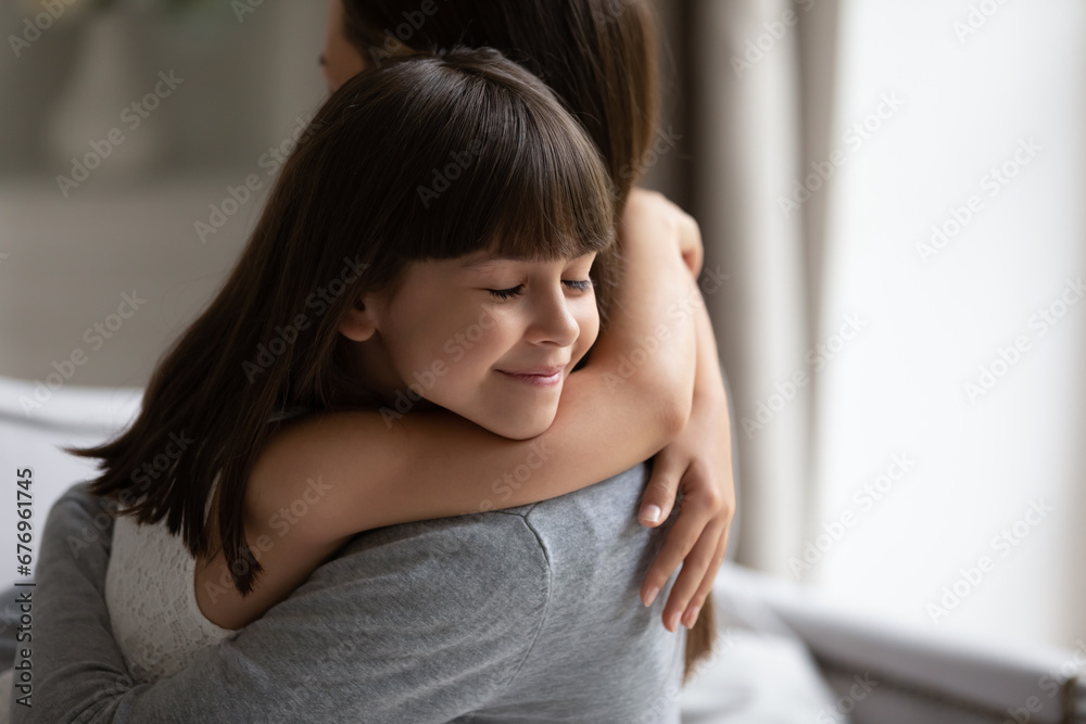 Close up cute little daughter with closed eyes hugging young mother or nanny, beautiful preschool girl embracing mum, family enjoying tender moment, good trusted relationship and bonding Close up cute little daughter with closed eyes hugging young mother or nanny, beautiful preschool girl embracing mum, family enjoying tender moment, good trusted relationship and bonding