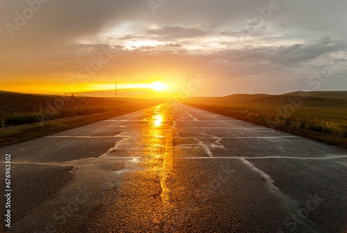 Beautiful shot of a road between fields under a cloudy sky during a sunset