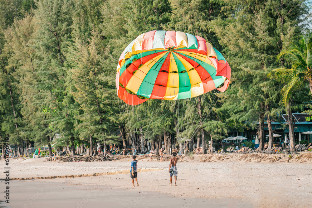 Two guys on beach keeping ready to fly in air colorful parachute. Bang Thao beach, Thailand