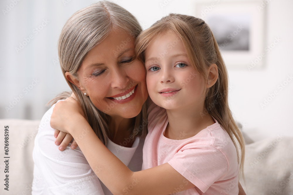 Happy grandmother hugging her granddaughter at home