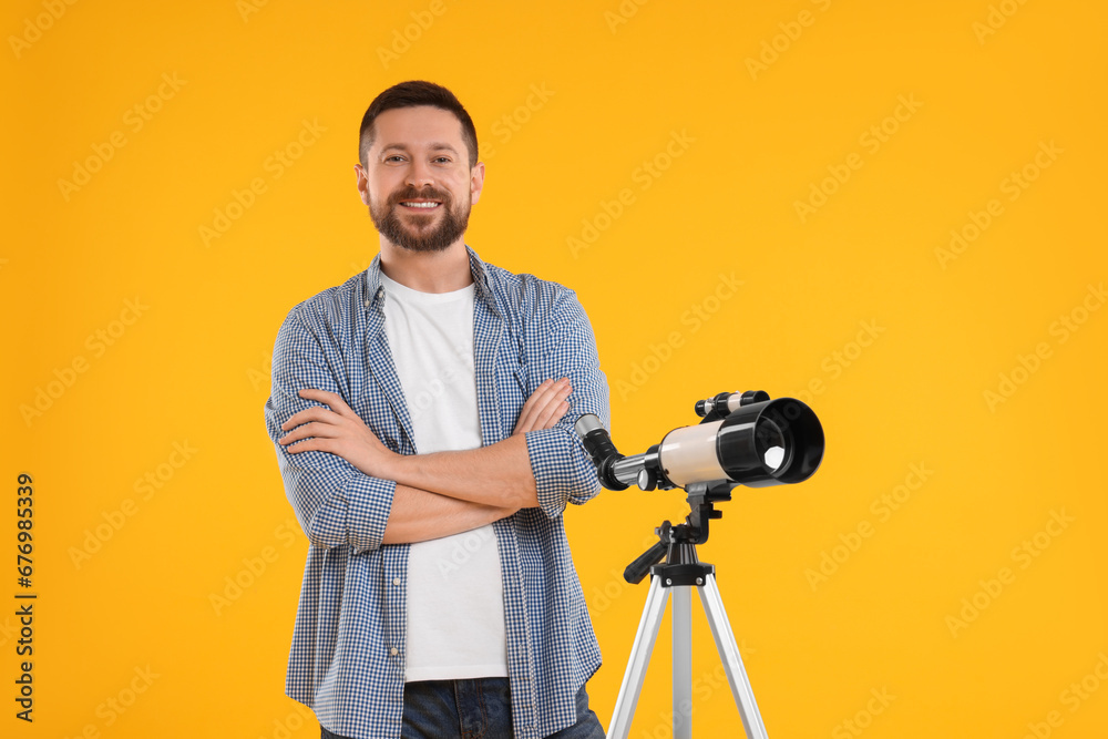 Happy astronomer with telescope on orange background