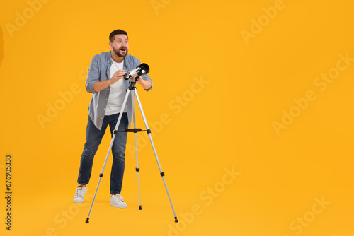 Fototapete Happy astronomer with telescope on orange background