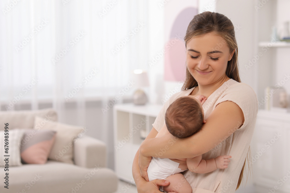 Mother holding her cute newborn baby in child's room, space for text Mother holding her cute newborn baby in child's room, space for text