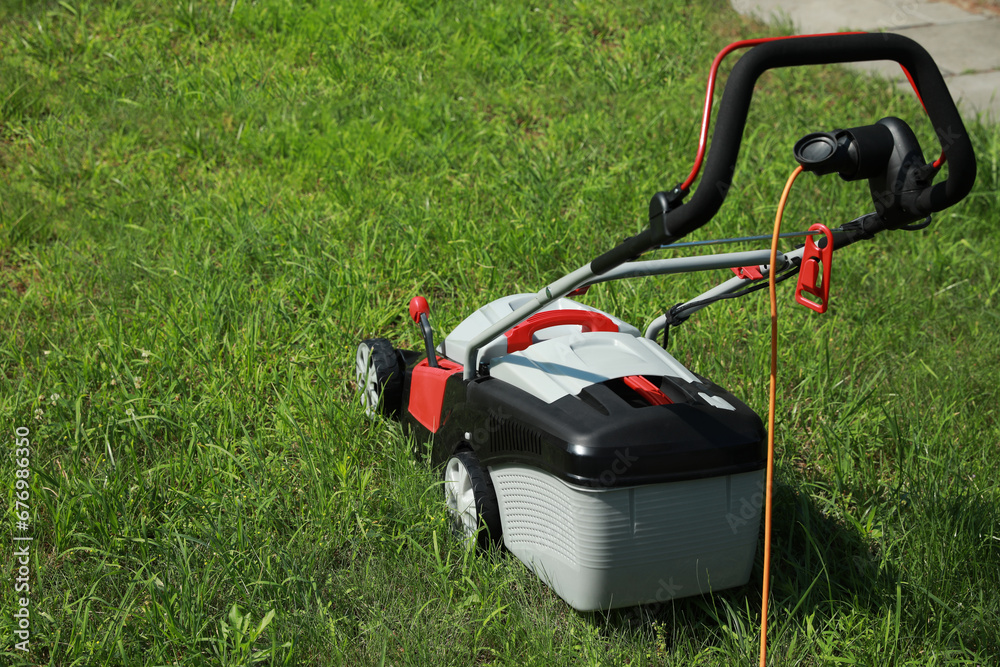 Lawn mower on green grass in garden, space for text Lawn mower on green grass in garden, space for text