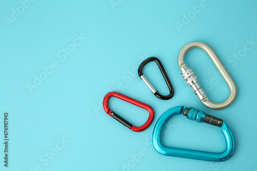 Metal carabiners on light blue background, flat lay. Space for text