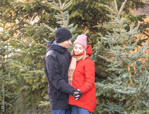 Happy woman and man hugging at Christmas Market in front of Christmas tree.