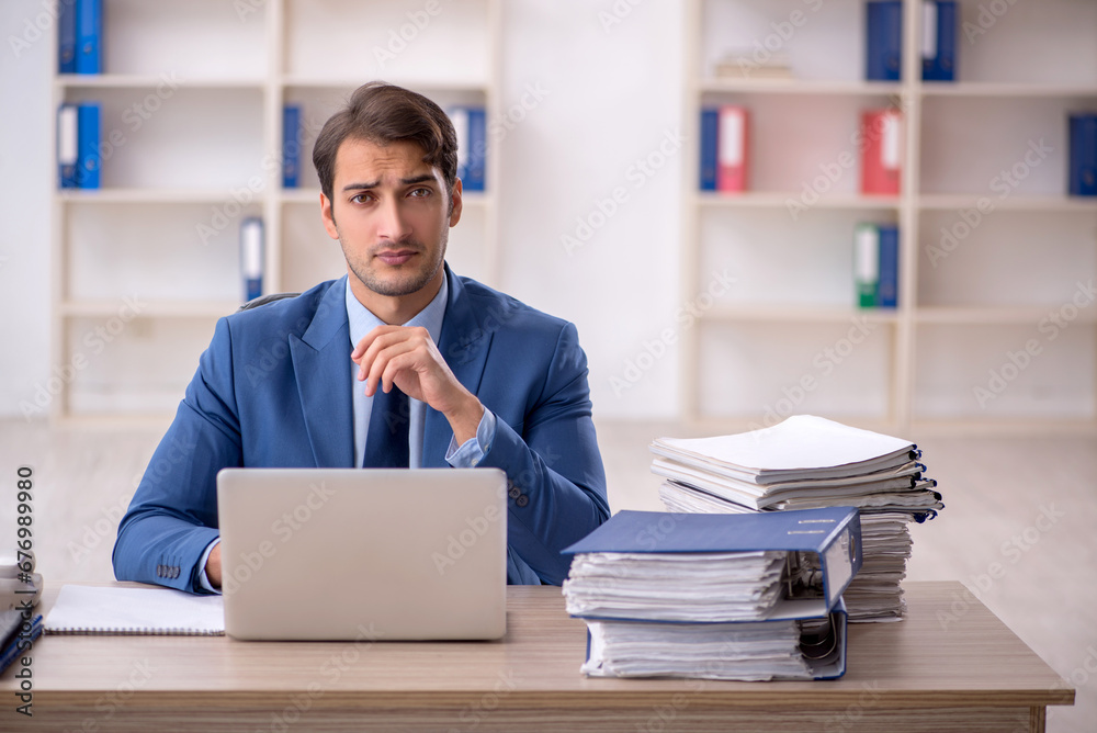 Young male employee and too much work in the office Young male employee and too much work in the office