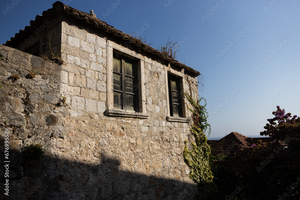 old stone house with closed shutters and a terracotta roof in an old European village on a hot summer afternoon