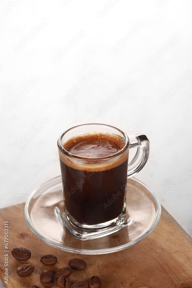 black coffee is served in a clear cup with a wooden base