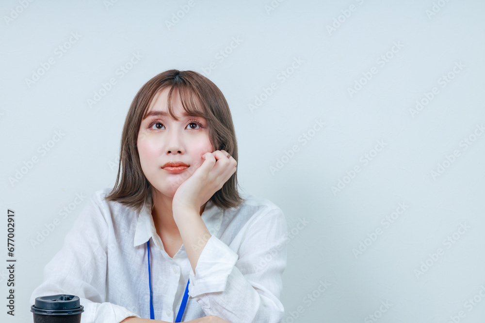 頬杖をつき考え事をする若い女性スタッフ 頬杖をつき考え事をする若い女性スタッフ