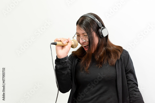 Beautiful asian woman (LGBTQ) is a singer. She enjoying sing a song or karaoke in music studio with microphone condenser and headphones for fun or voice creative photo